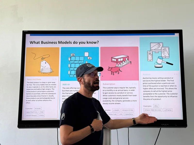 Eine Bildschirmfolie fragt "What Business Models do you know?" und zeigt bebilderte Geschäftsmodell-Beispiele.