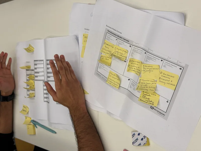 Nahaufnahme einer Hand auf einem großformatigen gedruckten Canvas voller Haftnotizen.